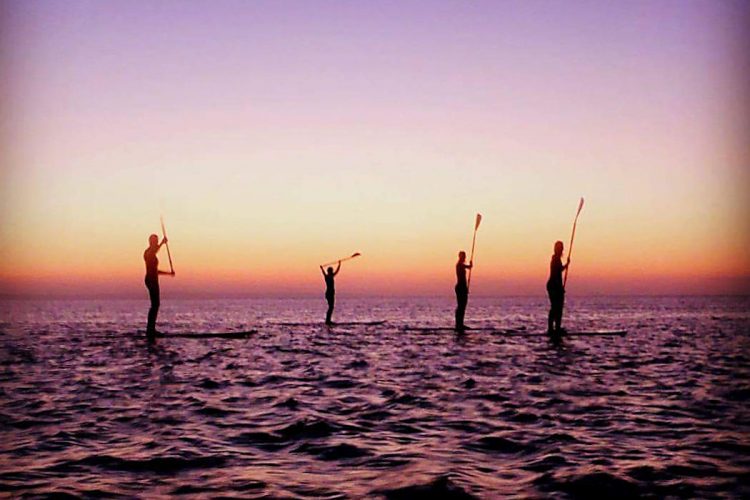 friends enjoying a paddleboarding sunset tour