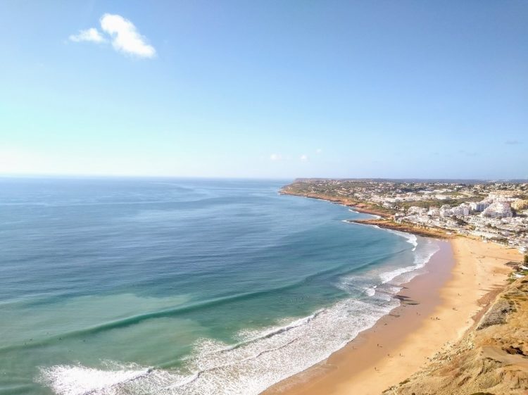 The vista across beach at Praia da Luz highlights the clear blue sea, golden sand and whitewashed village