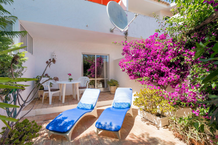 The front patio of Luz Mews is spacious offering a table, two chairs and two sunbeds
