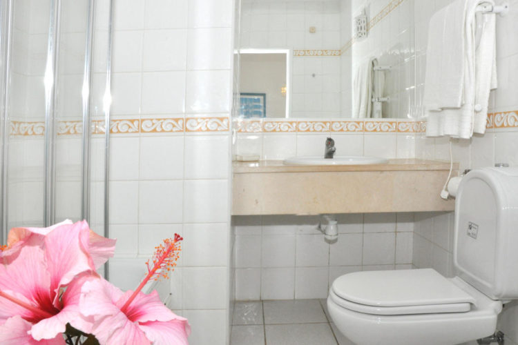 A white tiled bathroom at Ocean Villas Luz with stand up shower, toilet and sink