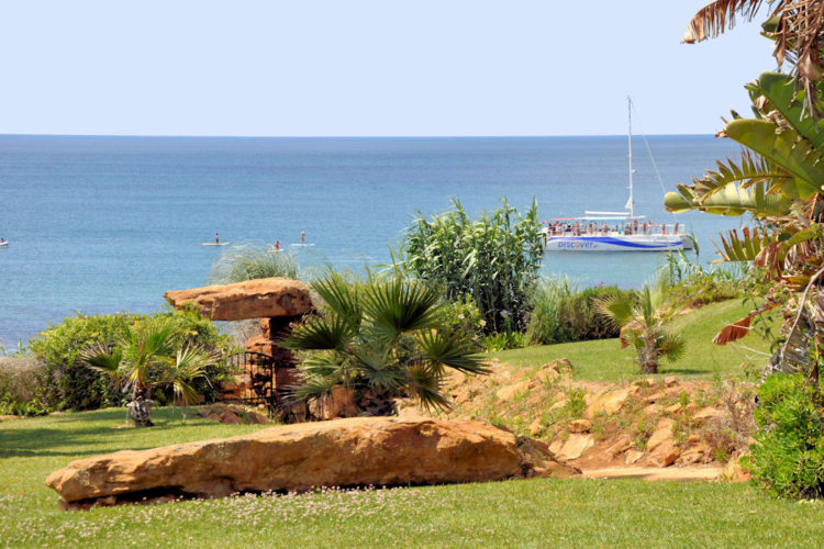 The west facing view at the gardens of Ocean Villas Luz look down upon the ocean and a catamaran