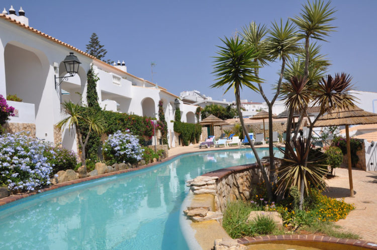 The swimming pool on the terrace is surrounded by gardens and the white apartments
