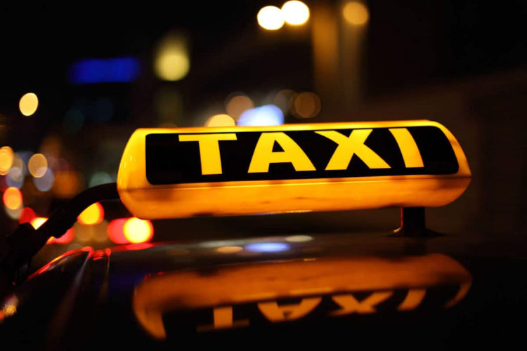 A yellow and black taxi sign on a nondescript taxi