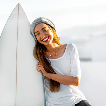 Smiling young girl cuddles her surf board